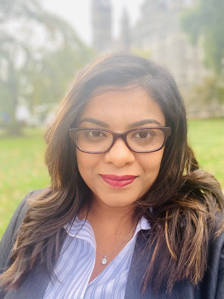 Purna Gamage wearing black glasses with a background of trees and grass