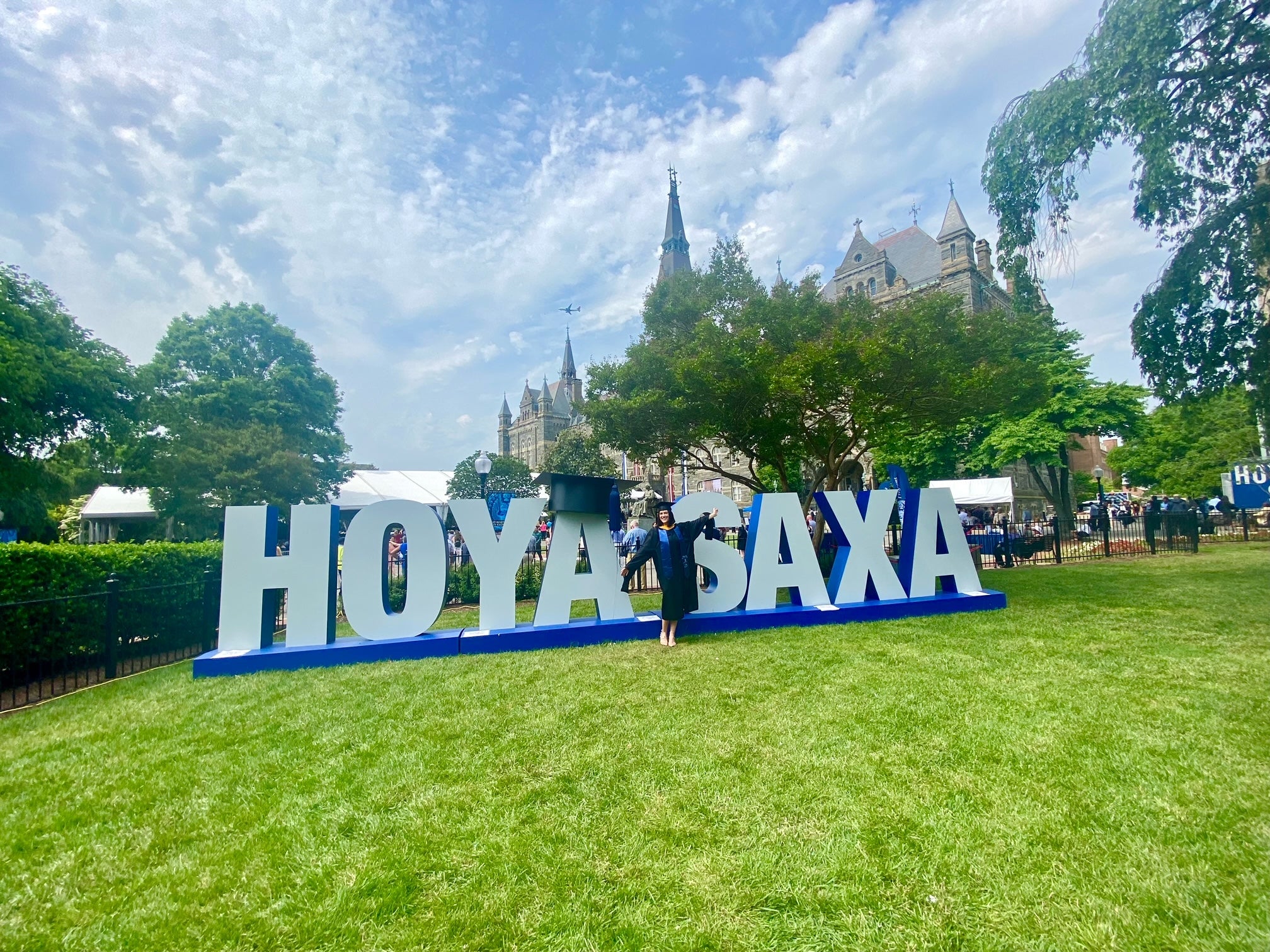 DSAN Graduate standing in front of the HOYA SAXA sign on the Healy Lawn