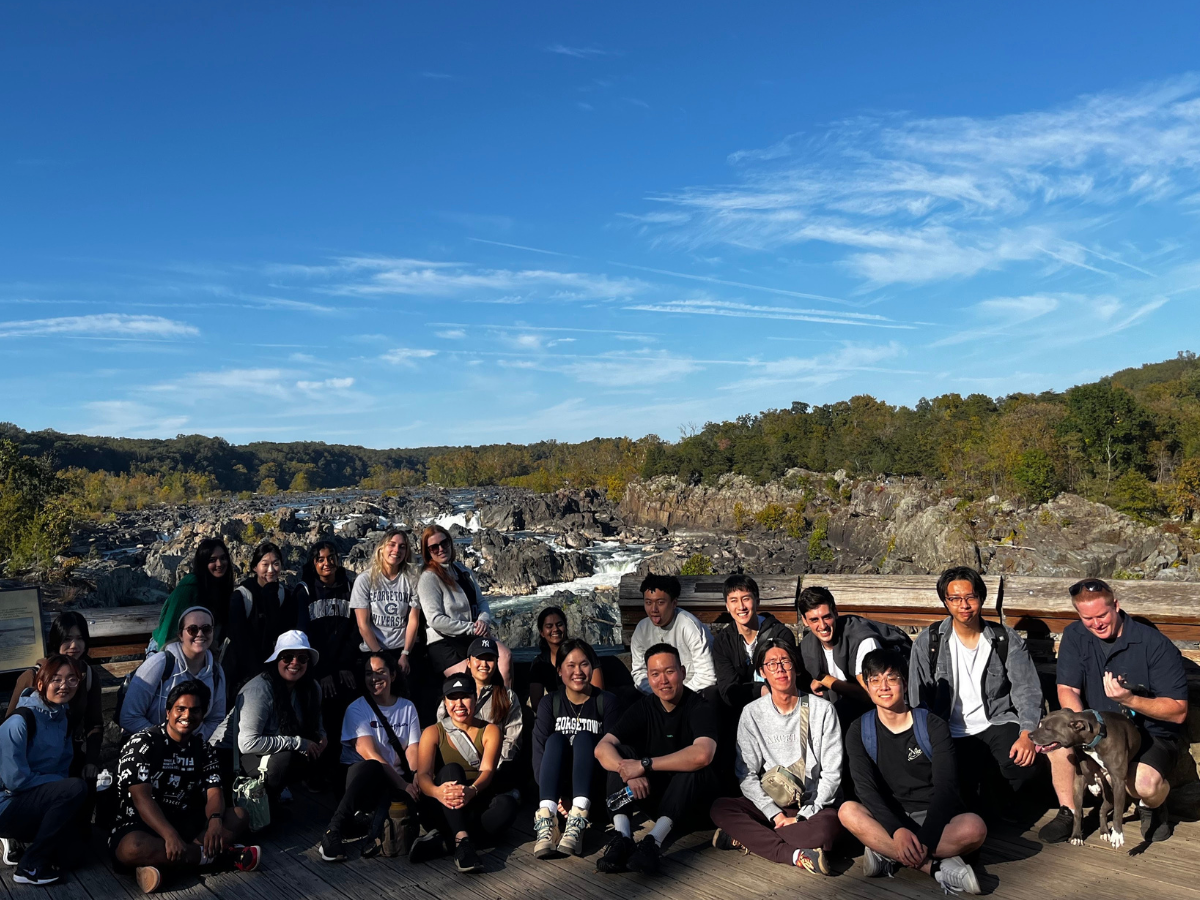 DSAN students take a group photo with the Great Falls in Virginia behind them.