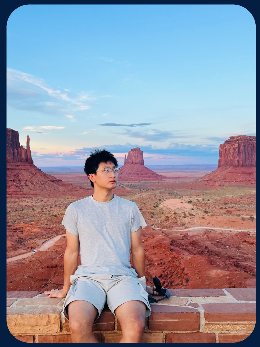 Chao Li sitting on a ledge in front of desert mountains.