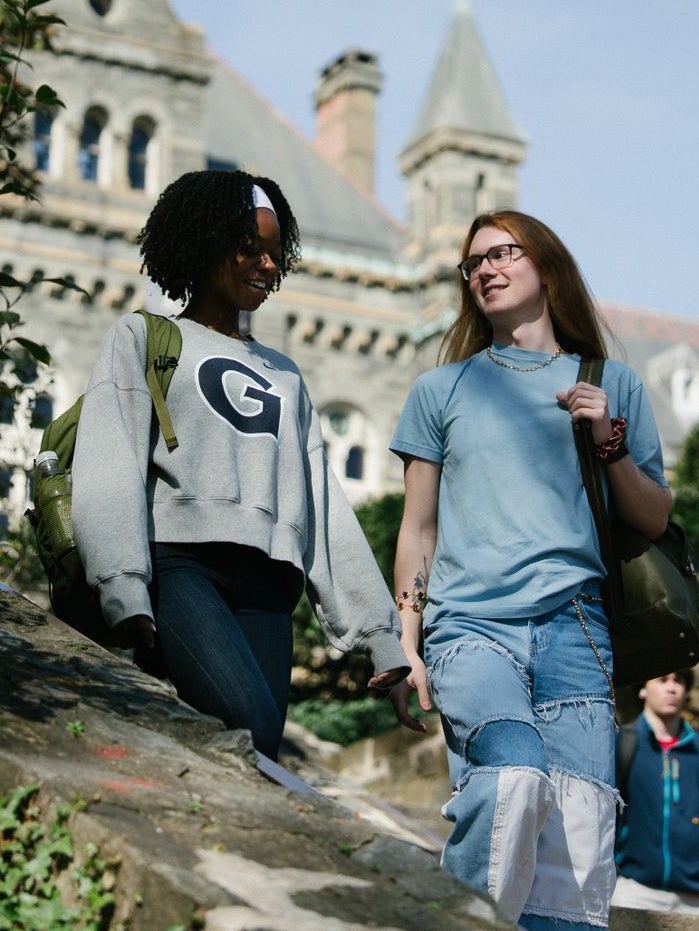 Two students walk down steps outside on main campus.