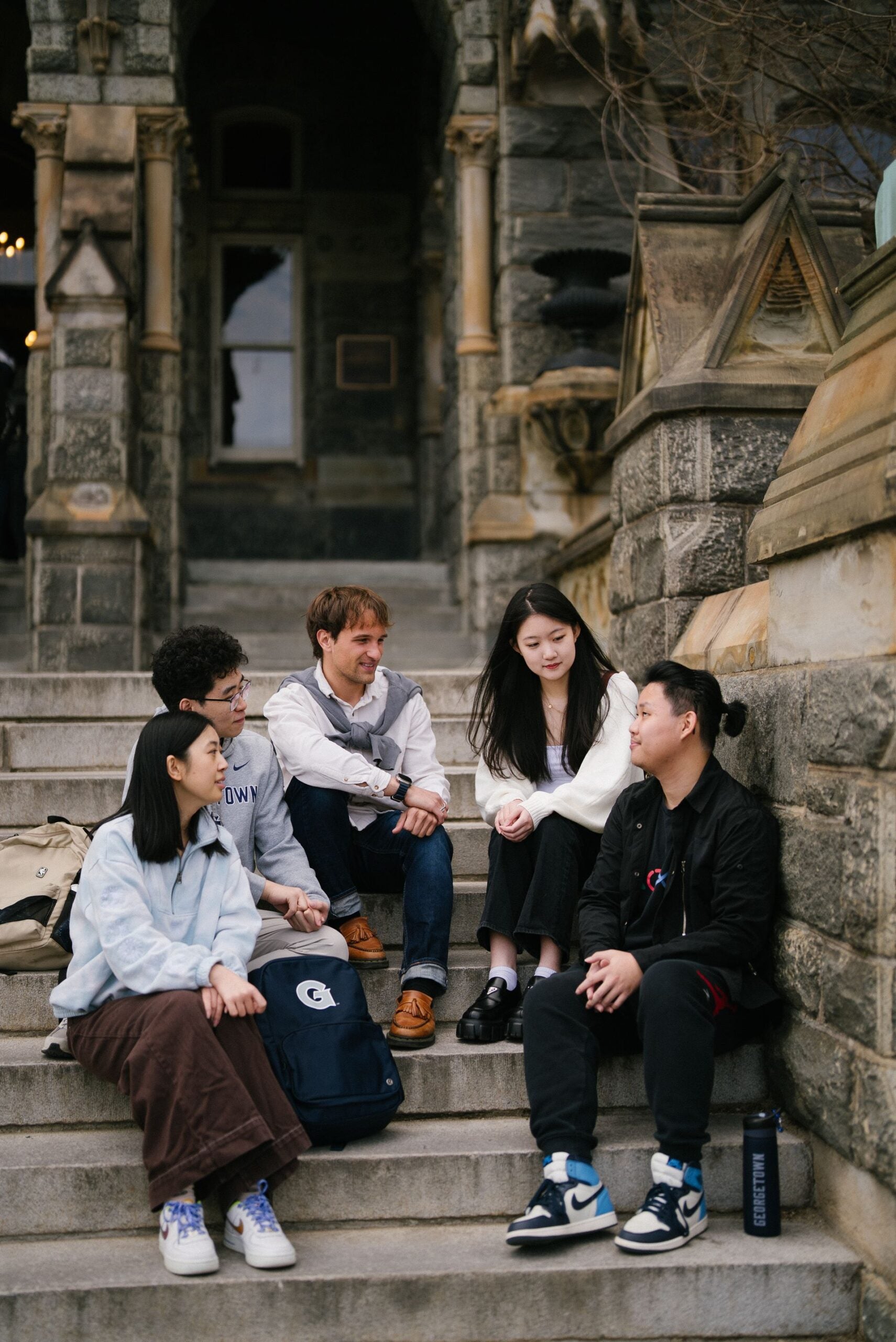 Students sitting on the steps of Healy Hall talking.