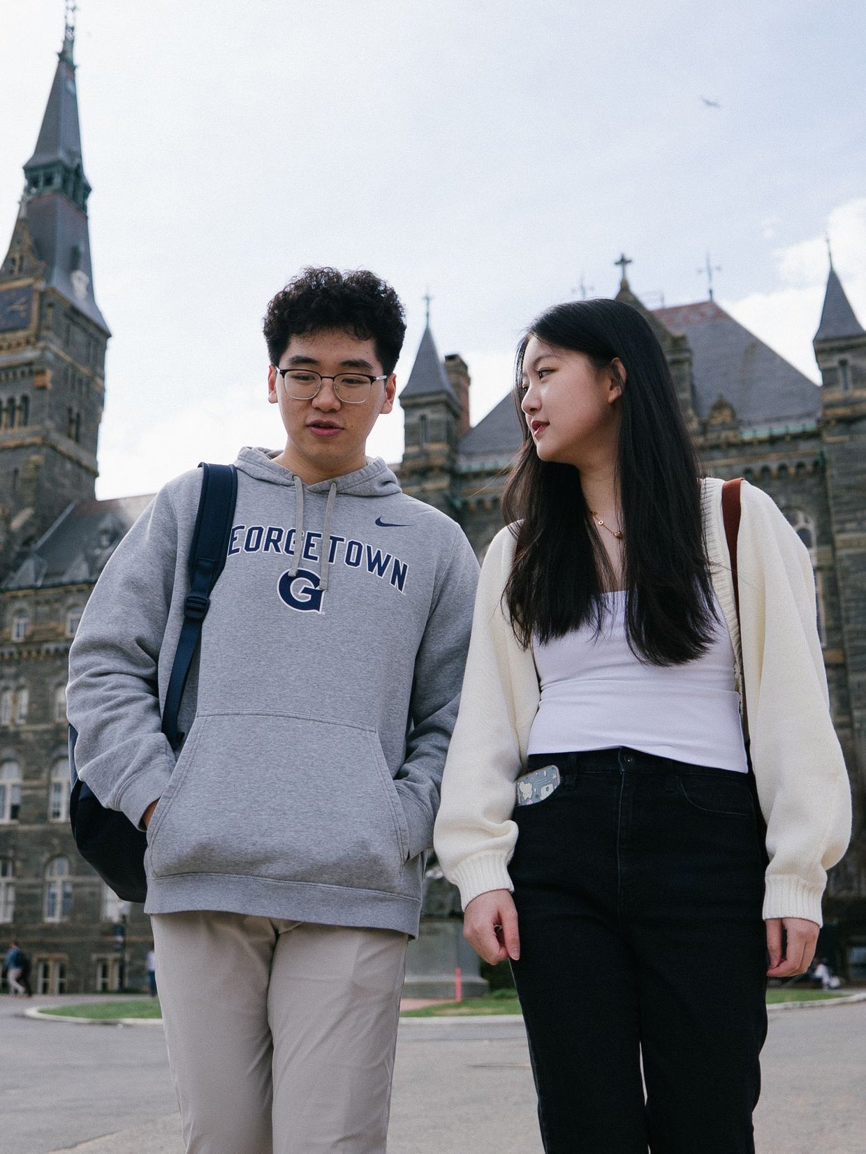 Two students walking together on main campus. Healy Hall is in the background.