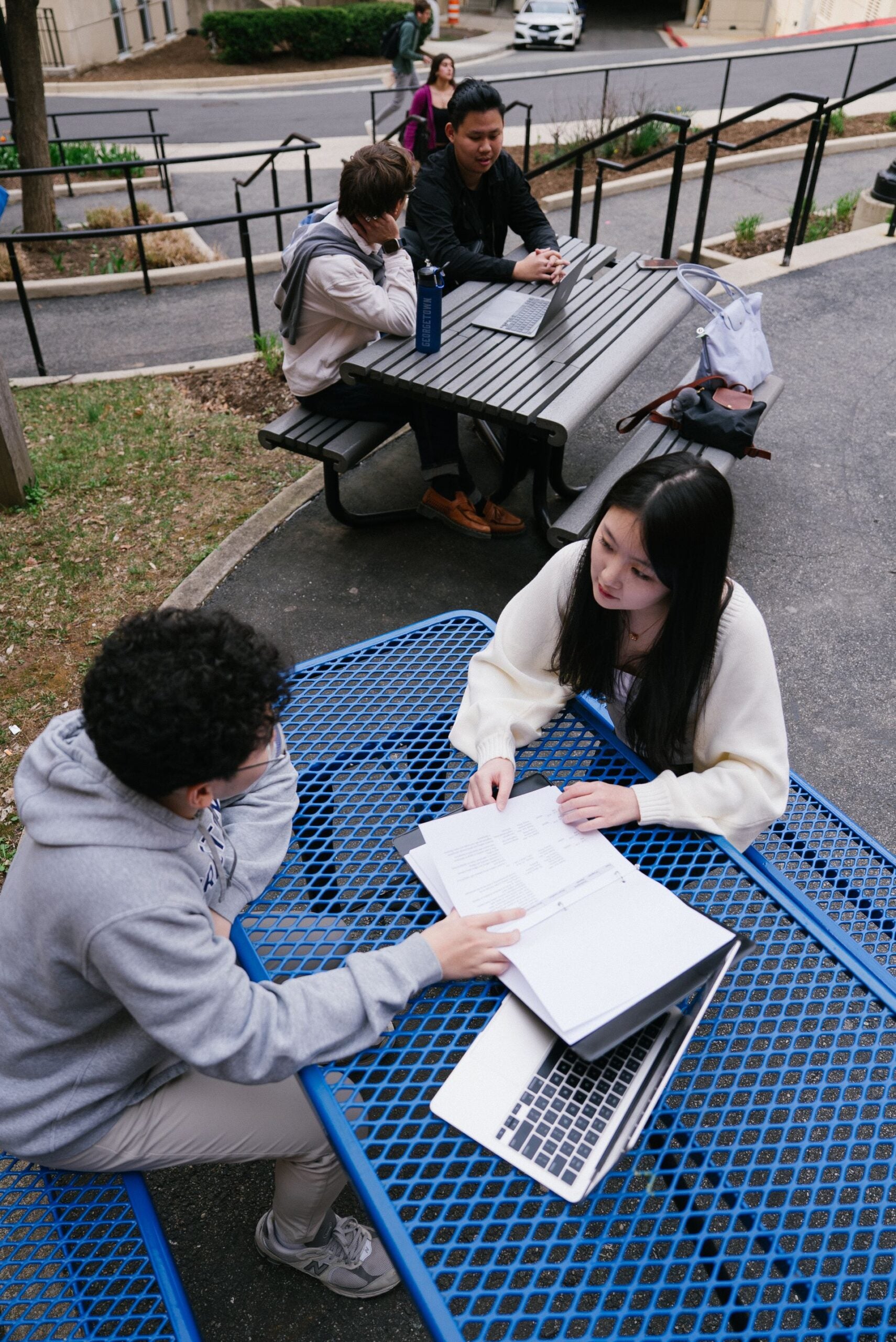 A group of students studying together outside at picnic tables.