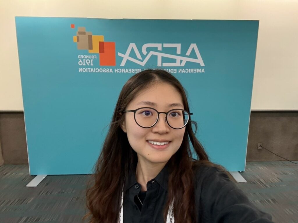Selfie of Yuxi in front of the AERA logo