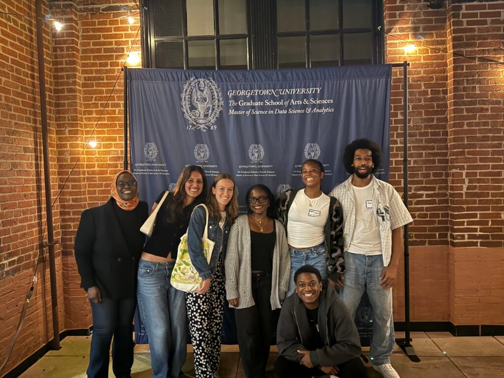 Group photo of students in front of the DSAN backdrop at our annual alumni mixer.